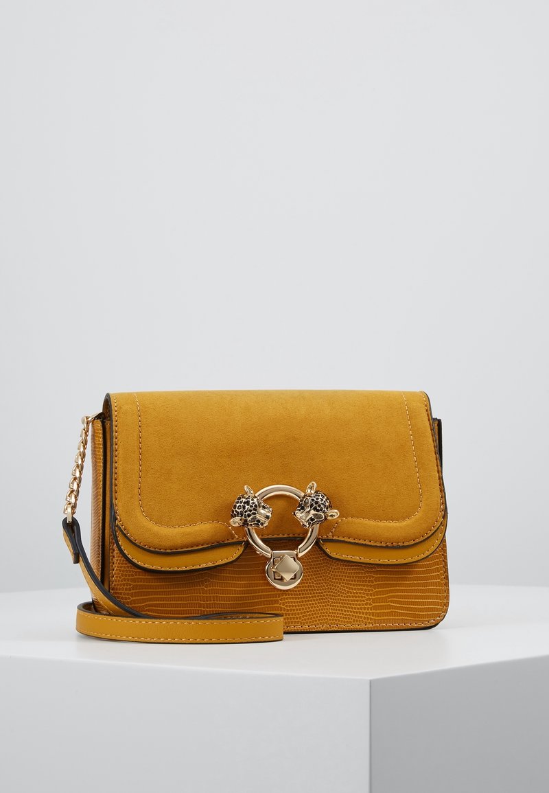 Borsa a tracolla in suede gialla con base testurizzata, dotata di una catena dorata e di una chiusura circolare decorata con dettagli a forma di testa di leopardo.