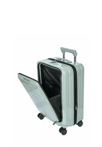Valise rigide de couleur vert menthe clair avec une surface texturée. Dispose d'une ouverture zippée, de sangles internes et de quatre roues pour la mobilité.