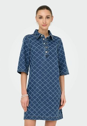 Denimklänning i mörkblått med diamantmönster, knapp-up krage, korta ärmar och en figurnära design, uppvisad med minimala tillbehör.
