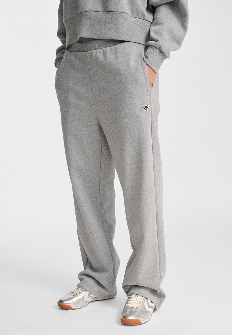 Graue Sweatpants aus weichem Stoff, mit elastischem Bund, seitlichen Taschen und einem kleinen Logodetail am Oberschenkel.