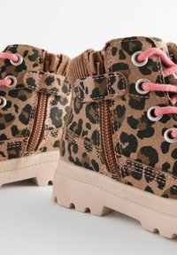 Bottines à imprimé léopard en suède marron et noir, avec des lacets roses, une fermeture éclair et une semelle en caoutchouc rose clair texturée.