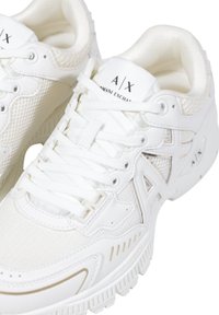 Sneaker sportive bianche con tomaia in mesh e sintetico, lacci piatti, collarino imbottito e suola in gomma testurizzata con accenti di branding.