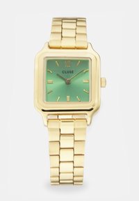 Montre carrée ton or avec un cadran dégradé vert, des index horaires rectangulaires et un bracelet à maillons. Nom de la marque "CLUSE" affiché.
