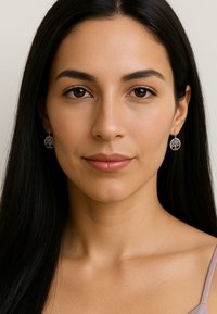 Smycken i silver med hängande örhängen i en cirkulär design som har ett trädmönster, fästa vid en delikat krok. Slät yta med intrikata detaljer.