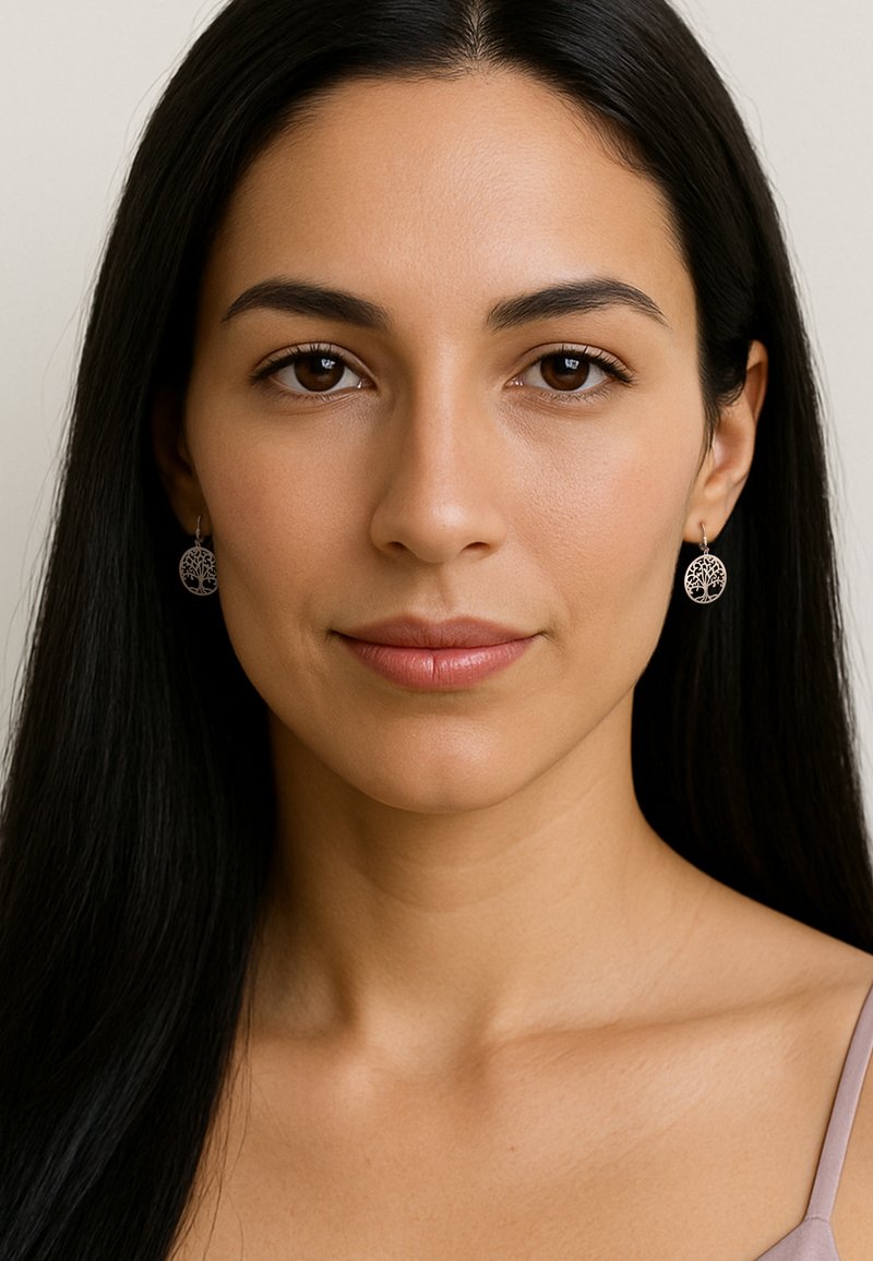 Smycken i silver med hängande örhängen i en cirkulär design som har ett trädmönster, fästa vid en delikat krok. Slät yta med intrikata detaljer.