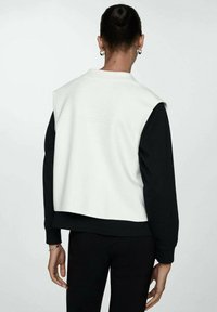 Sort og hvid cropped sweatshirt med en glat tekstur, der har et klart design med kontrasterende ærmer og en rund halsudskæring.