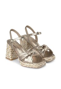 Sandali platform in oro metallico con design a strappi annodati, tacco a cuneo intrecciato e cinturino alla caviglia regolabile.