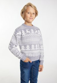Pulover tricotat de culoare gri deschis, cu modele albe de reni și fulgi de zăpadă, guler rotund și manșete și tiv cu nervuri. Asortat cu blugi albaștri.