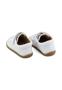 Zapatos de cuero blancos con punta redonda, que cuentan con una tira de velcro, un diseño perforado y una suela de goma marrón. Textura suave en todo el calzado.