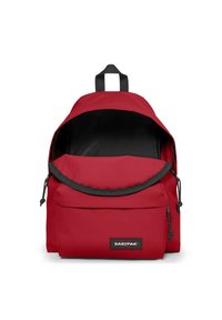 Sac à dos en nylon rouge avec un dessus arrondi, intérieur noir, bretelles ajustables et une poche avant avec une étiquette noire de marque.