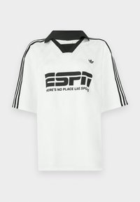 Bela majica kratkih rokavov s črnim ovratnikom, tremi črnimi črtami na rokavih ter drzno črno napisano besedilo, ki pravi "ESPN" in "NI KRAJA KOT ŠPORTI."