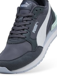 Ténis Puma com parte superior em têxtil cinza escuro, detalhes brancos e verdes, atacadores redondos e sola almofadada com detalhes texturizados.