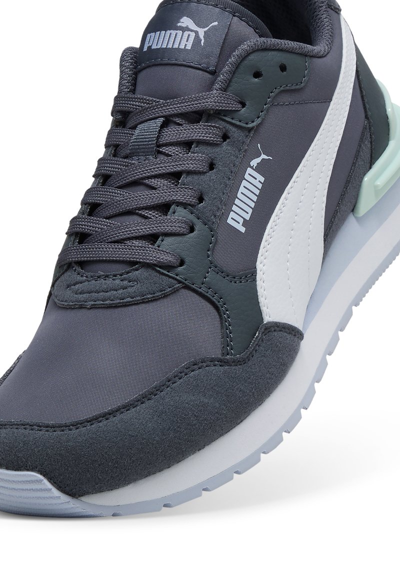 Zapatillas Puma con parte superior de textil en gris oscuro, detalles en blanco y verde, cordones redondos y suela acolchada con un acabado texturizado.