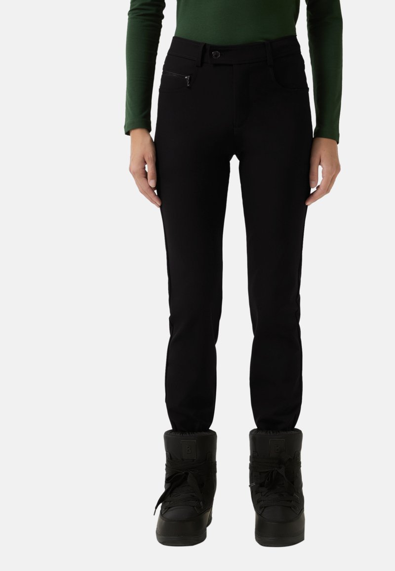 Black fitted pants with slim legs, made from soft material. Features a button closure and a zippered pocket. Worn with black, padded boots.