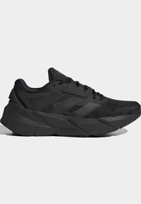 Black athletic shoes with mesh upper and rubber sole. Features a thick midsole, textured panels, and black laces. Minimalist design.