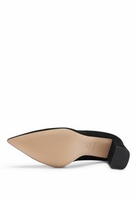 Chaussure noire à bout pointu avec semelle beige texturée et petit talon bloc, présentée semelle vers le haut sur un fond blanc.