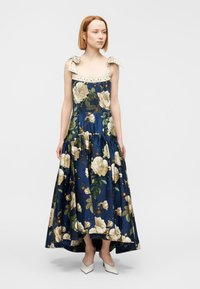 Μάξι φόρεμα με λουλούδια σε ναυτικό μπλε με κρεμ και χρυσές λεπτομέρειες. Διαθέτει δεσίματα στους ώμους, εφαρμοστό μπούστο και φουσκωτή, πολυεπίπεδη φούστα.