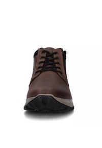 Scarpa in pelle marrone con accenti neri, design con lacci, suola in gomma robusta e cuciture a contrasto. Presenta una punta arrotondata e una superficie testurizzata.