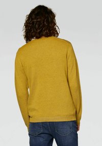 Mosterdgele gebreide trui met een ronde hals en geribbelde manchetten. De textuur is geweven en de pasvorm is ontspannen met een basisontwerp.