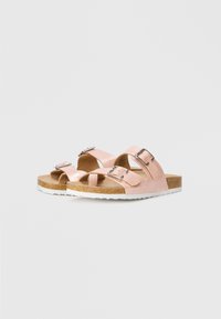 Ροζ σανδάλια με δύο ρυθμιζόμενους ιμάντες, μεταλλικές αγκράφες, φελλό για πάτο και λευκή υφή στην εξωτερική σόλα.