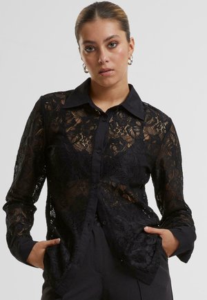 Black lace shirt featuring a classic collar, button-down front, long sleeves, and sheer floral patterns. Solid black cuffs and hem.
