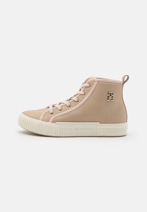 Baskets montantes beiges avec lacets, semelle blanche, logo en métal sur le côté et marquage "Tommy Hilfiger" sur la semelle en vue de profil.