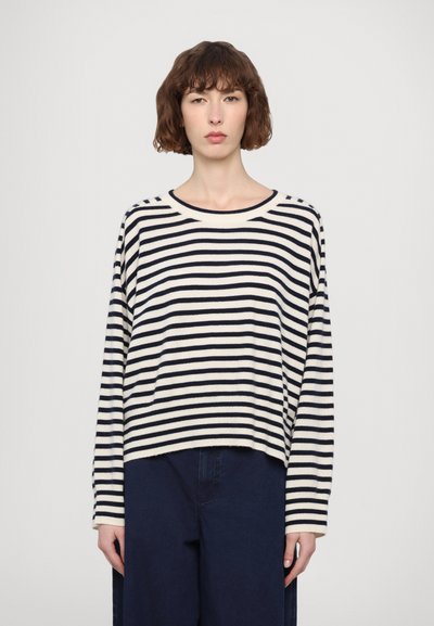Stribet langærmet sweater i creme og marineblå, med en afslappet pasform, rund halsudskæring og blød tekstur. Båret med mørkeblå brede benbukser.