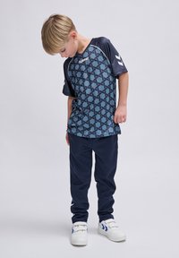 Blauw gestreept sportshirt met korte mouwen, gecombineerd met marineblauwe broek. Witte sneakers met blauwe accenten. Eenvoudig geometrisch ontwerp.