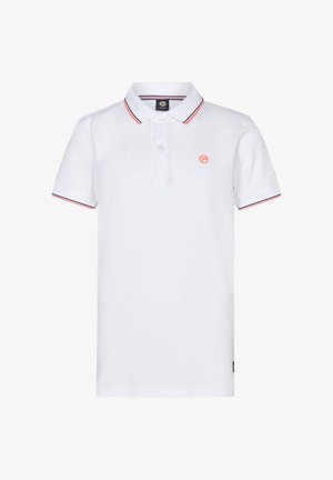 Weißes Poloshirt mit roten Akzenten, Jeansshorts und weißen Sneakers. Das Modell steht vor einem neutralen Hintergrund und zeigt die Details des Outfits deutlich.