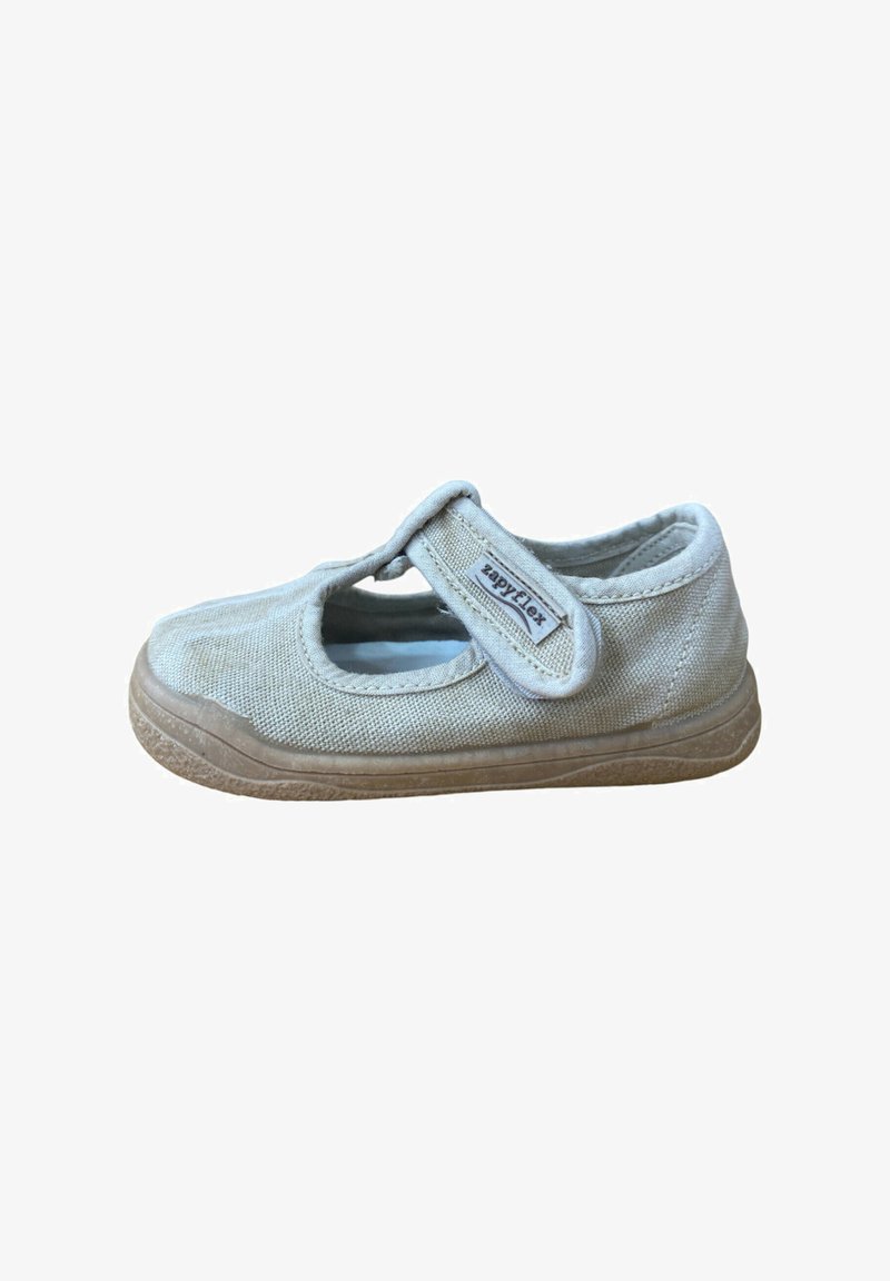 Zapato infantil Mary Jane de tela beige con tira ajustable de Velcro etiquetada como "Zapyflex" y suela de goma marrón texturizada.