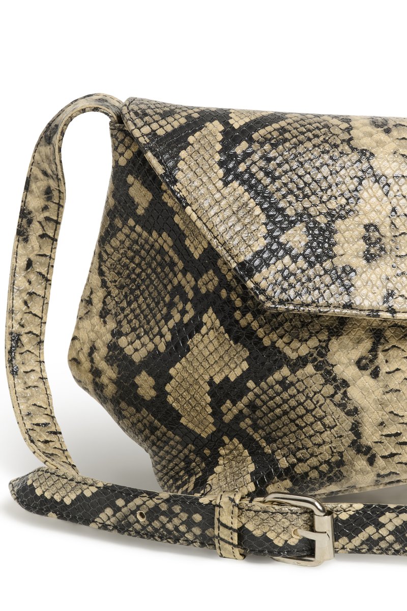 Sac à main beige et noir à motif peau de serpent avec fermeture à rabat et bandoulière ajustable équipée d'une boucle argentée sur fond blanc.