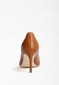 Chaussure à talon haut couleur tan avec un bout pointu et une texture en cuir lisse. Le talon aiguille est élégant, et la chaussure présente un design minimaliste.