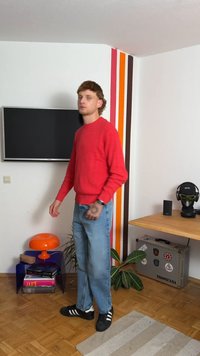 Punane kudumine sviiter, sinised teksad, mustad tennisetossud valgete triipudega. Tuba sisaldab telerit, oranži lampi ja mustrilist seina.