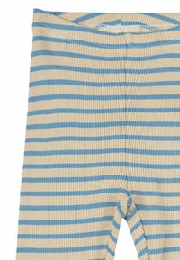 Leggings a coste di colore crema con strisce orizzontali blu. Presentano una cintura elastica larga e un design aderente delle gambe.