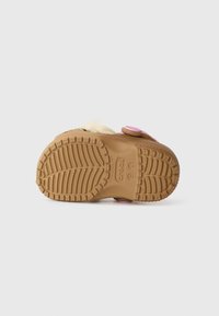 Brown rubber outsole with textured grip pattern, featuring a pink button accent. Designed for comfort and casual wear.