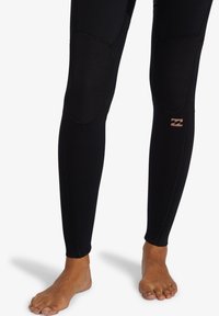 Leggings neri realizzati in un materiale elastico, con pannelli testurizzati sulle ginocchia e un piccolo logo sulla parte inferiore della gamba. Design aderente.
