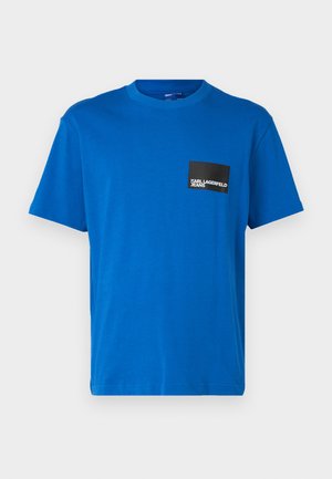 Blue cotton t-shirt with a round neckline, short sleeves, featuring a black square pocket with white logo text. Smooth texture.