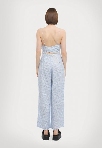 Conjunto em tom de azul claro com estampa floral, composto por um top cropped com alças finas e calças largas, realçado por um detalhe recortado nas costas.