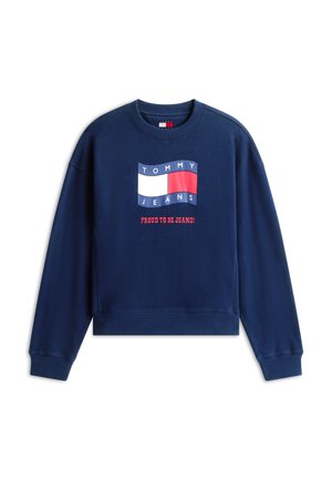 Hanorac bleumarin cu logo-ul Tommy Jeans în alb, roșu și albastru, și text roșu dedesubt cu mesajul „Mândru să port blugi!”