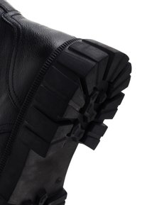 Stivale in pelle nera con suola in gomma resistente e scanalature profonde per una migliore trazione. Design strutturato, che evidenzia durabilità e presa.