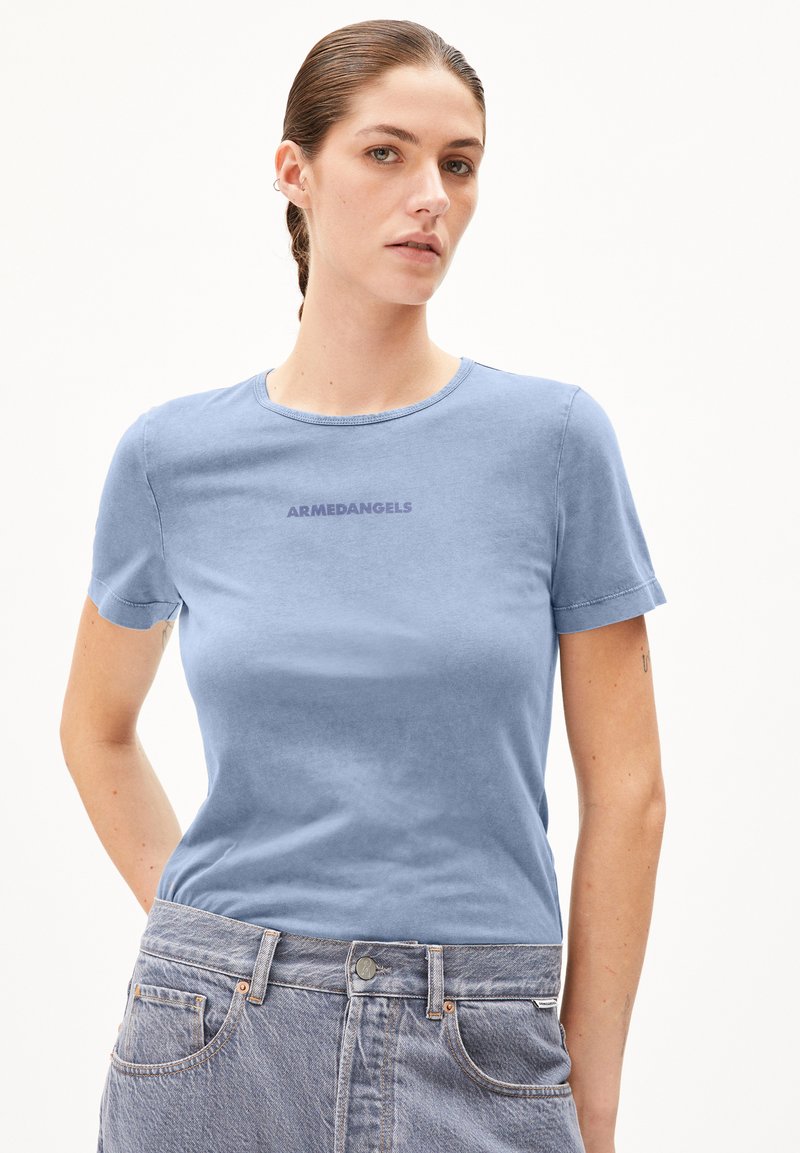 T-shirt bleu clair à col rond en tissu doux, avec des manches courtes et un logo "ARMEDANGELS" à l'avant dans une teinte plus foncée.