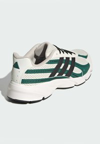 Biele športové tenisky s zelenými a čiernymi akcentmi, sieťovaným zvrškom, zaoblenou špičkou, retro dizajnom a odpruženou podrážkou s označením "CLOUDfoam".