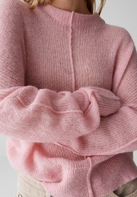 Maglione rosa lavorato a maglia con vestibilità ampia, caratterizzato da un collo alto, polsini a coste e un tessuto morbido e testurizzato.