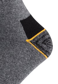 Graue Socken mit einem strukturierten Muster, featuring einer schwarzen Zehenkappe und gelben Nähten. Das Design umfasst einen gerippten oberen Rand und eine verstärkte Ferse.