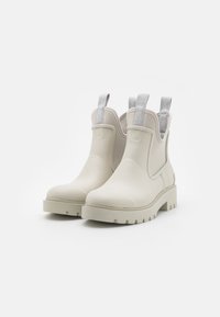 Botas de tobillo de goma blancas con suela gruesa, paneles laterales elásticos y tiradores que presentan la marca "Calvin Klein Jeans" en gris.