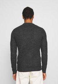 Mörkstickad tröja med långa ärmar, rund hals, ribbade mudd och nederkant, med en strukturerad yta i en djup grå färg.