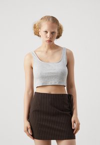 Grå ribbet crop top med brede stroppar, paret med en tettsittende mini skjørt i brune striper som har snøring på siden og rene linjer.