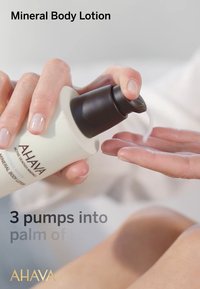 Mineralny balsam do ciała w białej butelce z czarną pompką. Balsam jest dozowany na dłoń. Gładka tekstura, lekki wygląd.