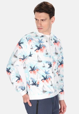 Chaqueta ligera con cremallera que presenta una base blanca con coloridos patrones de flores y veleros. Los puños y el dobladillo elásticos ofrecen un acabado ajustado.