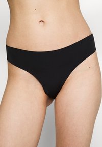Fekete bikini alsó sima, rugalmas anyagból, alacsony derekú kialakítással. Minimalista takarást és varrás nélküli széleket kínál a kényelem érdekében.